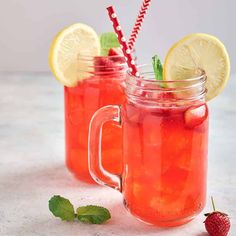 two mason jars filled with lemonade and strawberries next to minty garnish