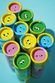 many different colored cups with faces drawn on the lids are stacked up in a pyramid