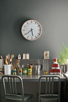 a kitchen counter with two chairs and a clock on the wall above it that reads 12 o'clock