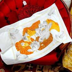 an orange and white pillow sitting on top of a red chair next to other pillows