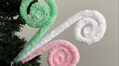 two towels hanging from a christmas tree on top of a white and pink ornament