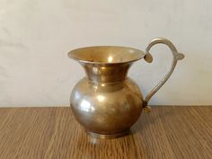 a brass pitcher sitting on top of a wooden table