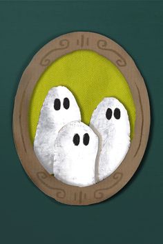 two white ghost faces in a circular frame on a green background with brown trim around the edges