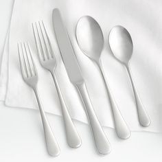 three forks, two spoons and one knife on a white table cloth with a napkin