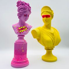 two plastic busturines one in pink and the other in yellow with red glasses