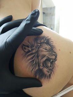 a person with black gloves on their hands and a lion tattoo on the back of his arm