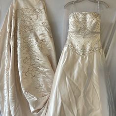 two wedding gowns are hanging on a hanger next to each other, one is white and the other is gold