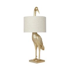 a gold bird lamp with a white shade on it's head and neck, sitting on a wooden base