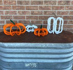 three decorative pumpkins sitting on top of a metal container next to a brick wall