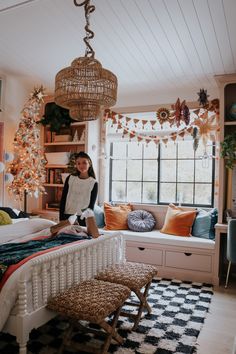 a woman sitting on top of a bed in a bedroom next to a christmas tree