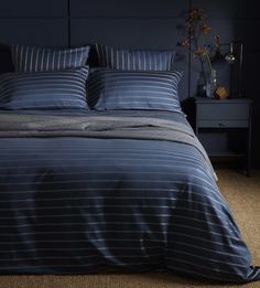 a bed with blue and white striped comforter in a dark room next to a night stand