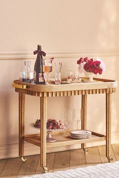 a wooden table topped with plates and glasses next to a vase filled with red flowers