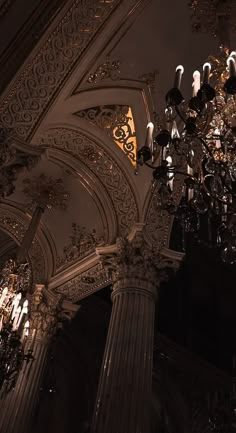 an ornate chandelier hangs in the middle of a room with columns and ceiling