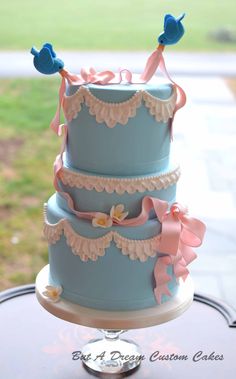 a three tiered cake with blue frosting and pink bows