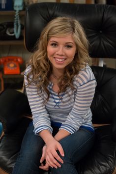 a woman sitting in a black chair smiling