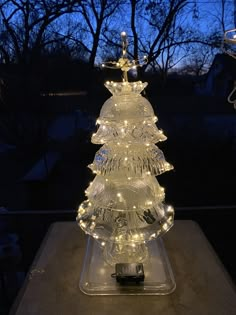 a lighted glass christmas tree sitting on top of a table