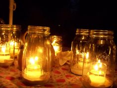 several mason jars filled with lit candles on a table