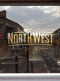 a window with the words north west written in gold on it and motorcycles parked outside