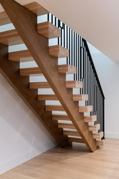 a wooden stair case with black and white railing