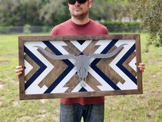 a man holding up a wooden sign with a cow skull on it