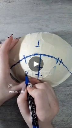 someone is drawing on a paper ball with blue crayons and writing on it