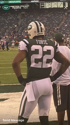 two football players standing next to each other on a field with fans in the stands