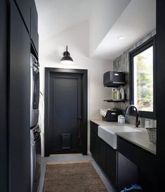 a kitchen with black cabinets and white counter tops, along with a rug on the floor