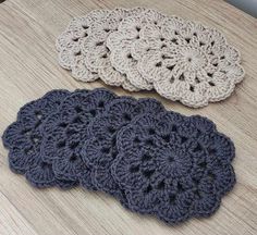 four crocheted coasters sitting on top of a wooden table