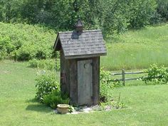 a small outhouse sitting in the middle of a field