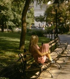 a woman is sitting on a park bench