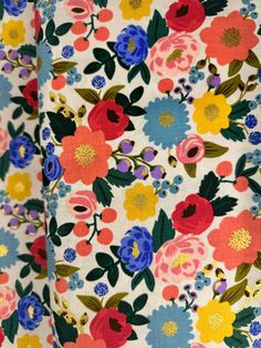 colorful flowers on white fabric with blue and yellow accents, closeup shot from the waist up