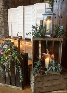 two wooden crates filled with plants and lit candles on top of a hard wood floor