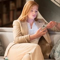 a woman sitting on a couch looking at her cell phone