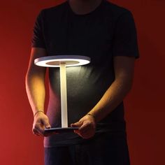 a man holding a tablet in his hands with a lamp on it's side