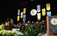 graduates are sitting at their graduation ceremony in front of the stage with banners and microphones