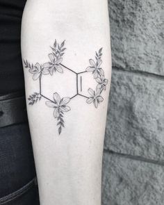 a tattoo on the leg of a woman that has flowers and leaves in hexagonic form