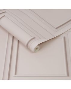 a close up view of the corner of a white cabinet door with a roll of paper on it