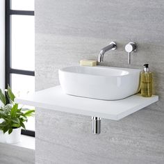 a white sink sitting on top of a counter next to a potted green plant