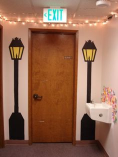 an exit sign is above the door to a bathroom with two lights on either side