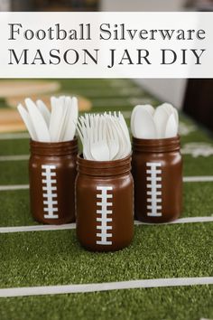 three mason jars filled with football silverware sitting on top of a green field