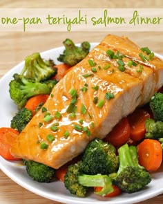 a white plate topped with salmon and broccoli on top of a wooden table