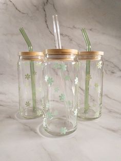 three glass jars with straws in them on a marble surface