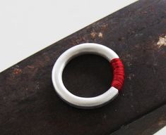 "This contemporary modern ring is made from sterling silver, cast with a polymer concrete inlay and Wrapped with red nylon thread. The clean Minimalist design makes this unique and timeless piece and it looks great alone or stacking, the red thread makes it a perfect Christmas gift. Ring width 0.14' / 3mm * The Ring is available also in in 22k gold plated brass - You can contact the studio for a quote through etsy. * This Ring can also be ordered in solid gold - You can contact the studio for a Handmade Minimalist Red Rings, Modern Handmade Red Ring, Modern Handmade Red Rings, Concrete Inlay, Concrete Jewelry, Cube Necklace, Red Thread, Big Rings, Modern Ring