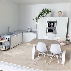 a kitchen with white chairs and a wooden table