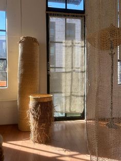 two tall vases sitting on top of a wooden floor next to a sheer curtain