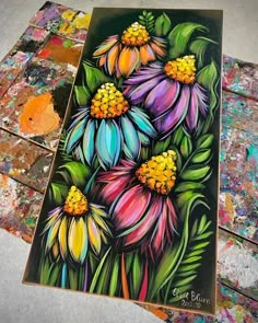 a painting of colorful flowers on a piece of paper with paint chips in the background