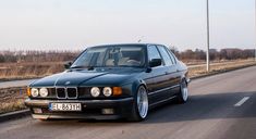 a black bmw parked on the side of an empty road in front of a car