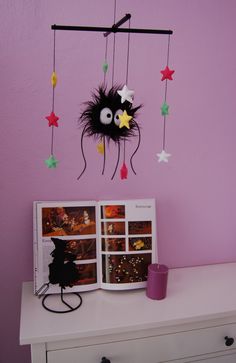 a purple wall with a black monster hanging from it's side next to a white dresser