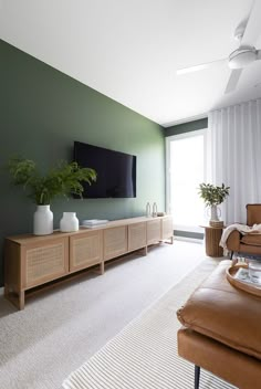 a living room filled with furniture and a flat screen tv on top of a wooden cabinet