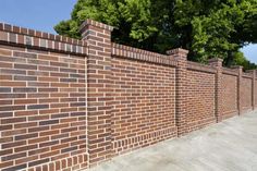 a brick fence with trees on the side and blue sky in the backround